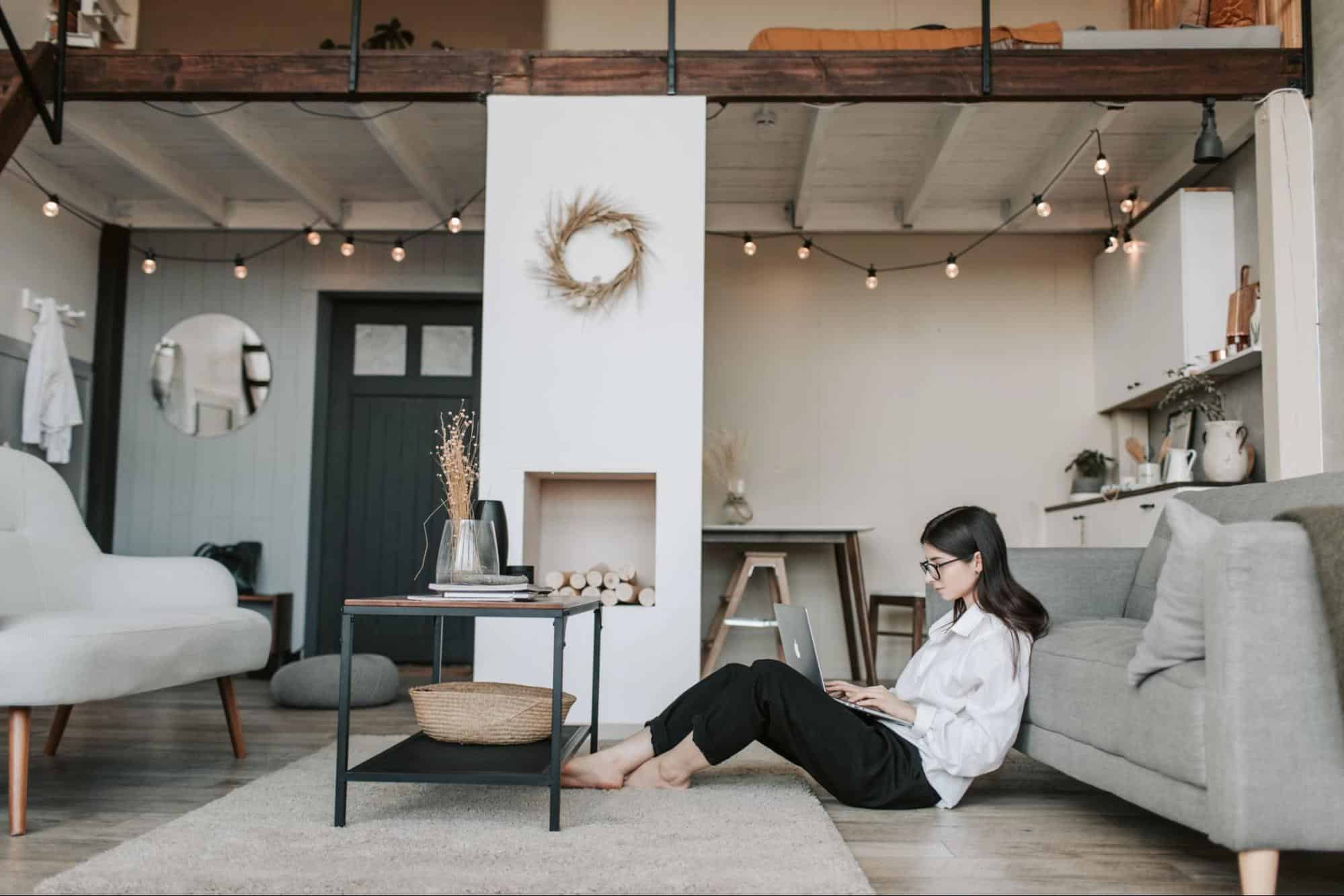 Lady in a living room sitting on the floor on a laptop.