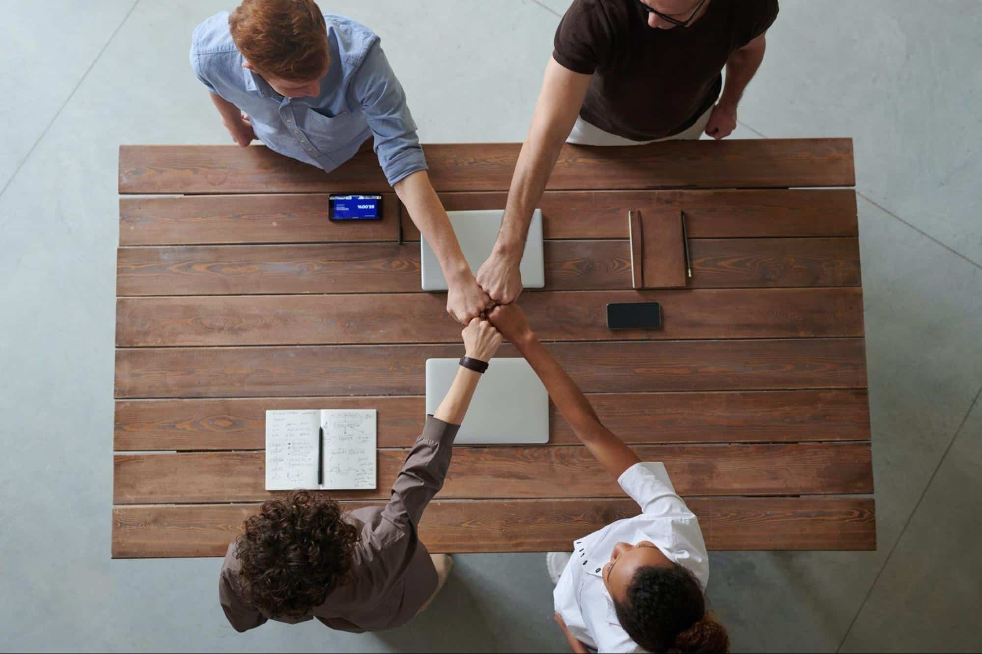 Group of 4 people fist bumping.